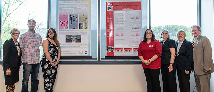 Students, faculty and administrators pose next two two research posters.