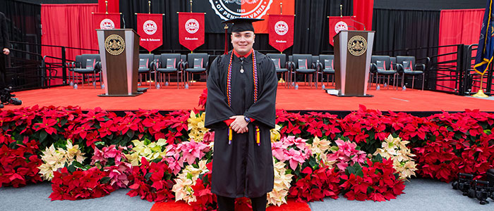 Alex Walsh stands in front of the stage of graduation day.