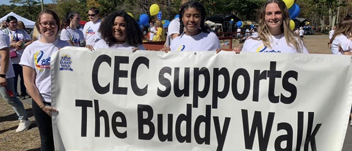 3 students holding a banner that says CEC Support the Buddy Walk