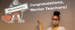 A student points to a sign that eads “Congratulations, Warrior Teachers!